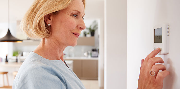 A woman using a smart thermostat